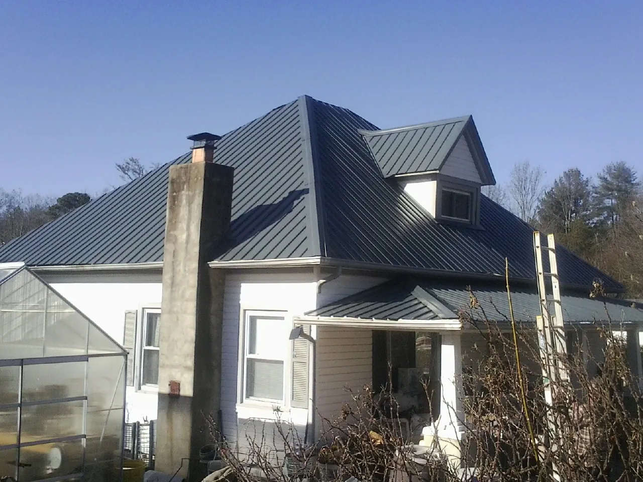 Dark blue standing seam metal roof on a white farmhouse with dormer — Slate & Tile Roof Repair by Roofing Brothers in Lincolnville