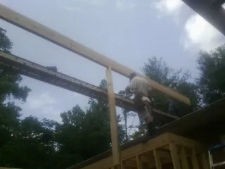 Carpenter setting a ridge beam over a new addition frame — Ice Dam Removal by Roofing Brothers in Lincolnville