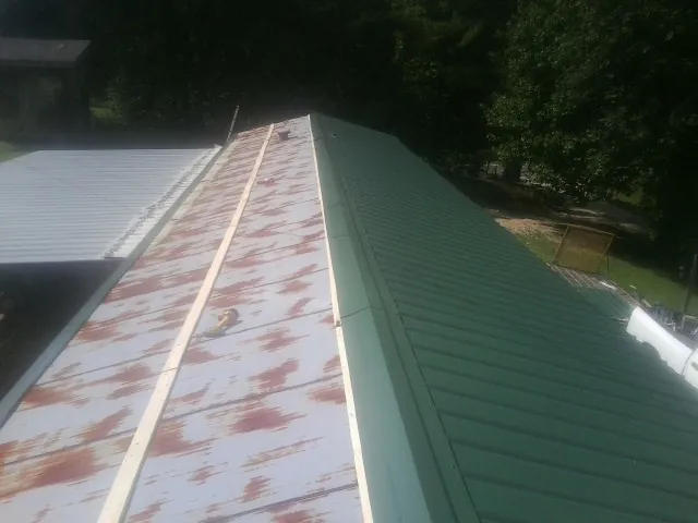 Old rusted panels beside newly installed green metal roofing — Wind Damage Roof Repair by Roofing Brothers in Lincolnville