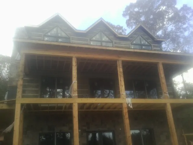 Dormers and porch framing on a large log home under construction — Roof Coating work by our crew in Lincolnville