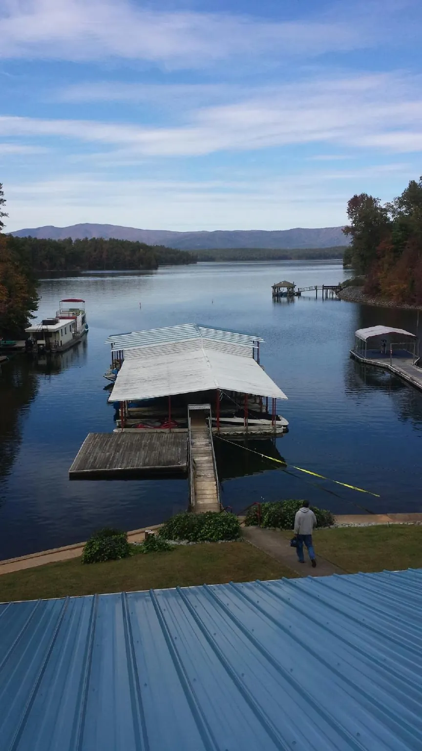 View across a lake from a newly installed blue metal roof in Lincolnville