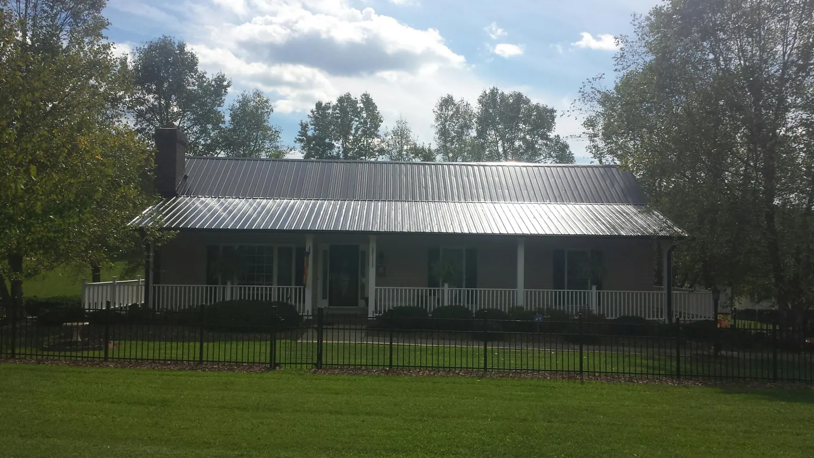 Gray metal roof on a brick ranch with a full width front porch — Gutter Guard Installation work by our crew in Lincolnville