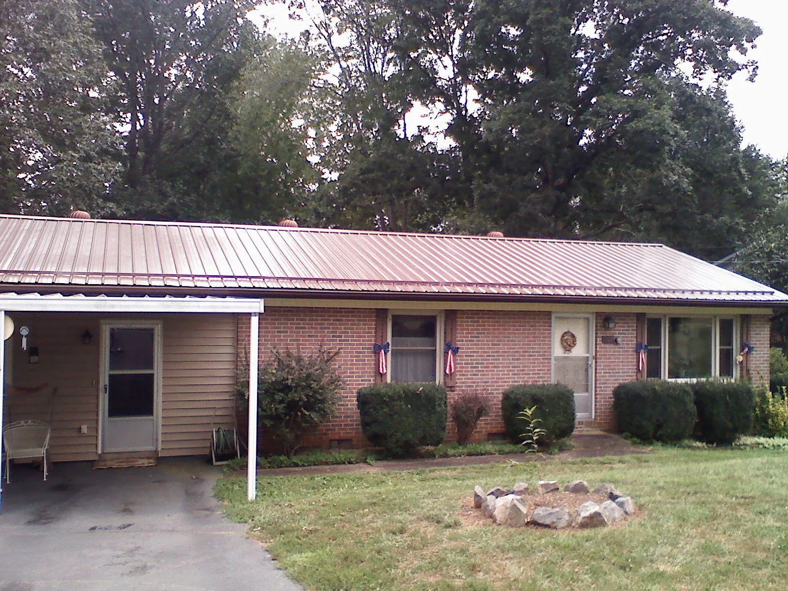 Bronze metal roof and carport on a brick ranch home — Roof Repair work by our crew in Lincolnville