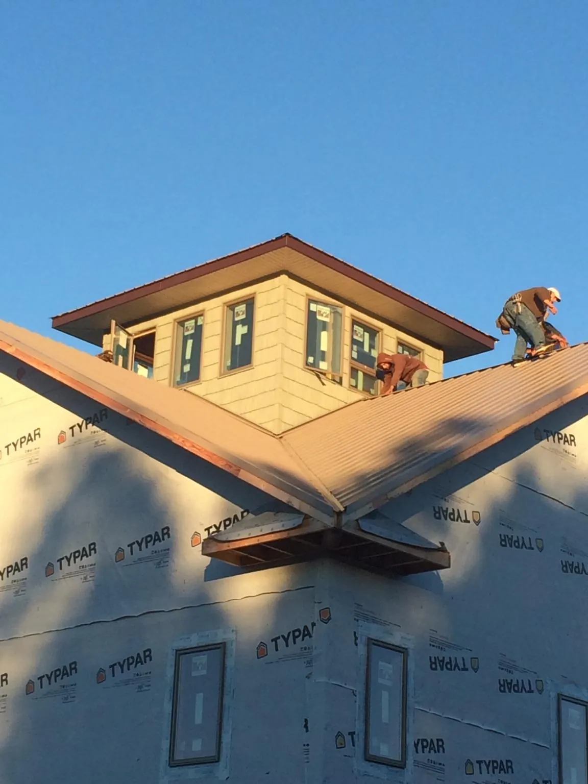 Roofers working around a rooftop cupola on a new metal roof at sunset — Roof Waterproofing in Lincolnville by Roofing Brothers